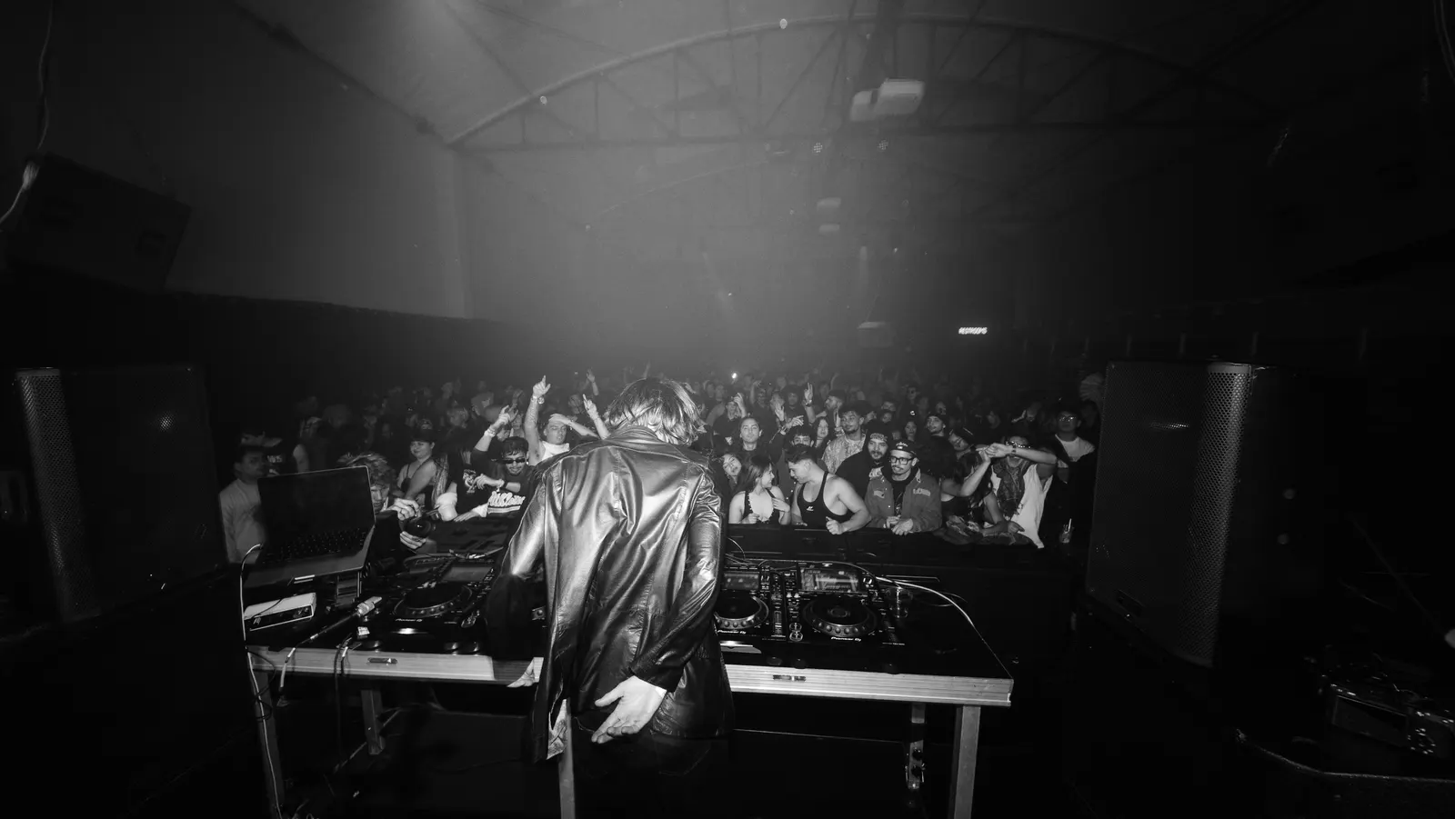 A DJ facing a full floor